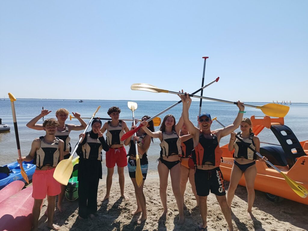 journées de la glisse à Bombannes édition 2024. Les 8 apprentis du Campus du Lac brandissent rames et canoé pour une photo souvenir