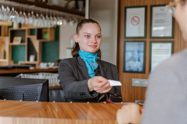 jeune fille à l'accueil qui rend un ticket au client